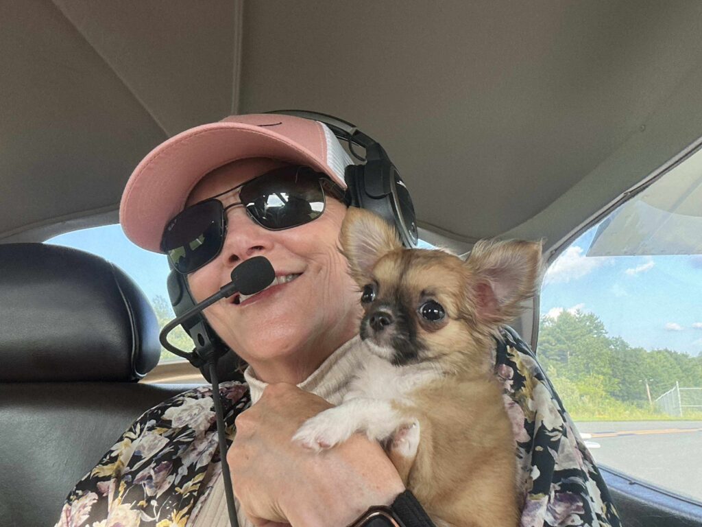 Pilot holding small dog in cockpit