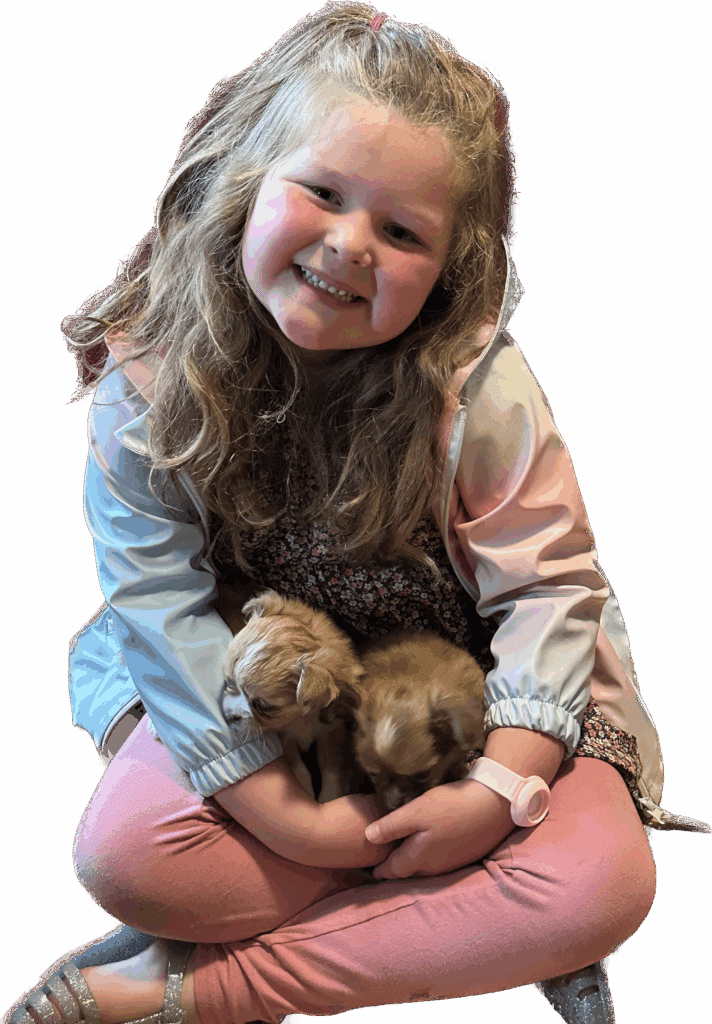 Smiling girl holding two small puppies in her lap.